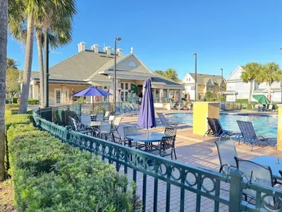 a pool with chairs and a table and umbrella at 3 Bedroom 2 Bathroom Villas At Seven Dwarfs 30-105 in Kissimmee