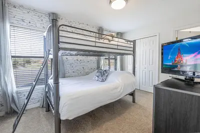 a bedroom with a bunk bed and a flat screen tv at 6BR Fun Villa – Game Room, Pool, Near Parks in Kissimmee