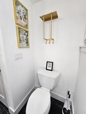 a bathroom with a toilet and two pictures on the wall at Comfy Tiny Home WP Large Private Deck Queen bed in Orlando