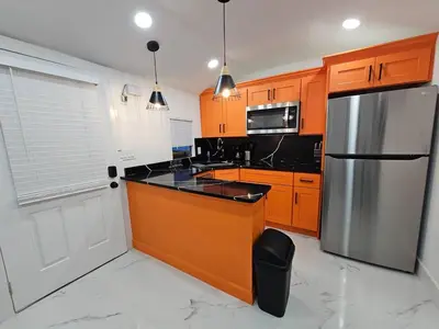 a kitchen with orange cabinets and a stainless steel refrigerator at Comfy Tiny Home WP Large Private Deck Queen bed in Orlando