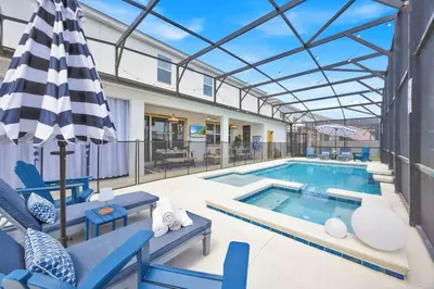 a swimming pool with blue chairs and an umbrella at The Venue Mansion in Kissimmee