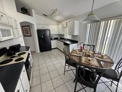 a kitchen with a table and a black refrigerator at Relaxing 3BR/2BA Home - Just 15 Minutes from Disney! in Kissimmee