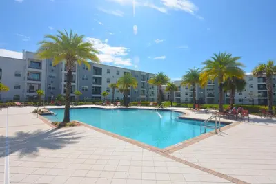 a swimming pool with palm trees and a building at Storey Lake Resort Condo next to Disney in Kissimmee
