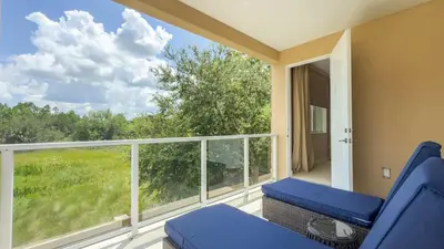 a balcony with a blue chair and a large window at Modern Magic Village Home for 12 with Grill 3131 in Orlando