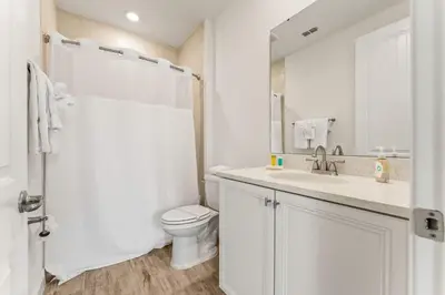 a white bathroom with a toilet and a sink at Waves of Relaxation - For 8 in Orlando
