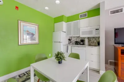 a kitchen with a white table and green walls at 2 Mi to Disney and Old Town Resort Condo with Perks in Orlando
