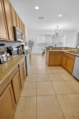 a large kitchen with wooden cabinets and a tile floor at 290 LF - BellaVida Cozy 6BR Pool Home in Kissimmee