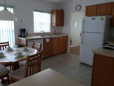 a kitchen with a white refrigerator and wooden cabinets at Lake Therapy by Paradise Resort Vacations in Orlando