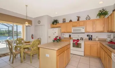 a kitchen with wooden cabinets and a table and chairs at Sunset Bliss Escape by Paradise Resort Vacations in Kissimmee
