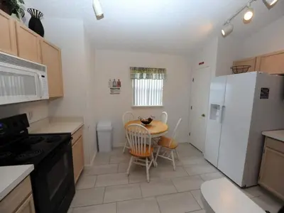 a kitchen with a table and a white refrigerator at Palmview Villa by Paradise Resort Vacations in Orlando