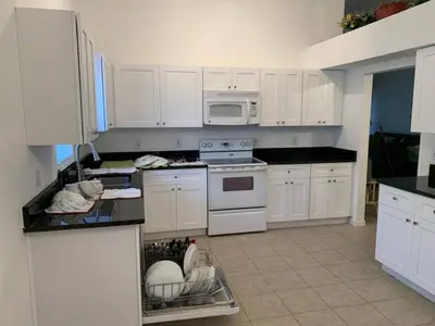 a kitchen with white cabinets and white appliances at Holiday Hideout in Orlando