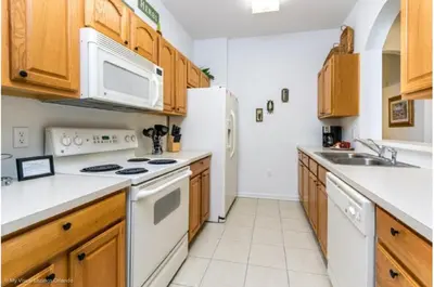 a kitchen with white appliances and wooden cabinets at Three-Bedroom Apartment Kissimmee in Orlando