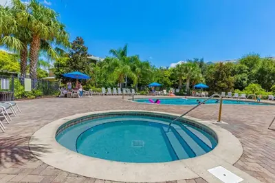 a swimming pool in a park with people sitting under umbrellas at Three-Bedroom Apartment Kissimmee in Orlando