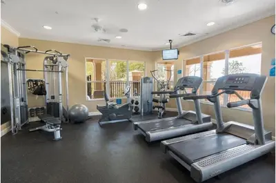 a gym with treadmills and machines in a room at Three-Bedroom Apartment Kissimmee in Orlando