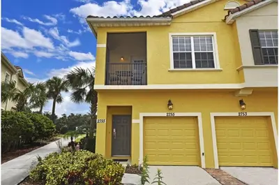 a yellow house with two garage doors at Two-Bedroom Townhome Kissimmee in Orlando