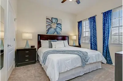 a bedroom with a large bed with blue curtains at Two-Bedroom Townhome Kissimmee in Orlando