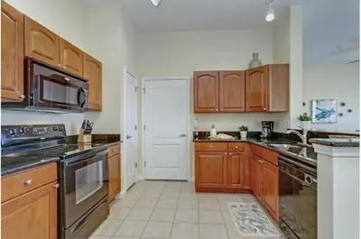 a kitchen with wooden cabinets and a stove top oven at Two-Bedroom Townhome Kissimmee in Orlando