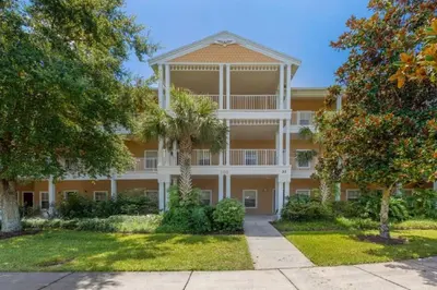 an exterior view of a large apartment building with trees at Three-Bedroom Townhome Kissimmee in Orlando