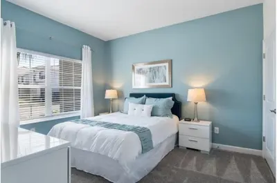 a blue bedroom with a bed and a window at Four-Bedroom Townhome Kissimmee in Orlando