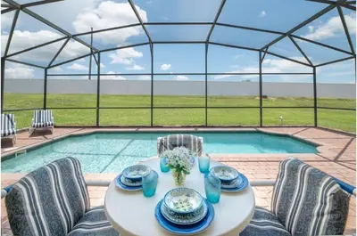 a table and chairs in front of a pool at Three-Bedroom Pool Home Kissimmee in Orlando