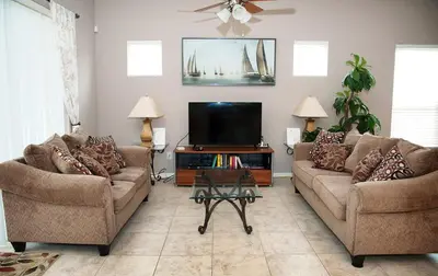 a living room with two couches and a flat screen tv at Four-Bedroom Pool Home Kissimmee in Orlando