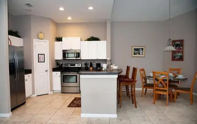 a kitchen with white cabinets and a table with chairs at Four-Bedroom Pool Home Kissimmee in Orlando