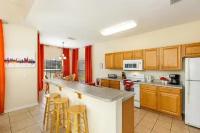 a kitchen with wooden cabinets and a white refrigerator at Five-Bedroom Pool Home Kissimmee in Orlando