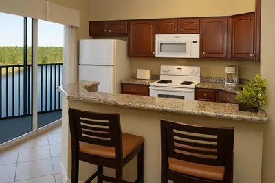 a kitchen with a counter and two chairs in a room at Luxury 3-bed Condo Near Disney Worldquest Resort in Orlando