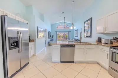 a large kitchen with white cabinets and stainless steel appliances at 4-Bed Home Near Disney Private Pool in Kissimmee