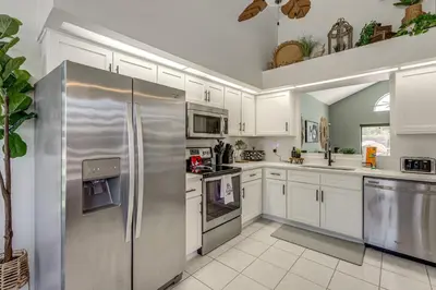a kitchen with white cabinets and stainless steel appliances at Disney Getaway with Private Hot Tub 14 Mi to Parks in Kissimmee