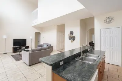 a kitchen and living room with a sink and a couch at Casa 5 Quartos Vista Lago – Perto da Disney! in Kissimmee