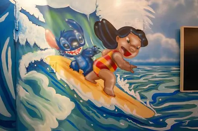 a mural of mickey and stitch on a surfboard in the water at Surf and Sun Stitch Studio Kissimmee in Kissimmee