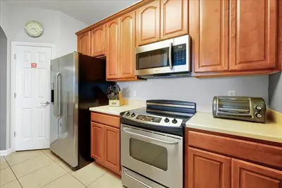 a kitchen with wooden cabinets and stainless steel appliances at Vista Cay Resort Minutes to Parks & Magic! in Orlando