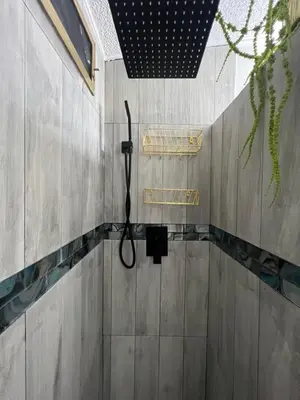 a shower in a bathroom with a hose on the wall at Luxury Tiny Cottage 5 miles from Disney in Kissimmee