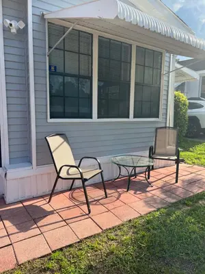 a patio with two chairs and a glass table at Luxury Tiny Cottage 5 miles from Disney in Kissimmee