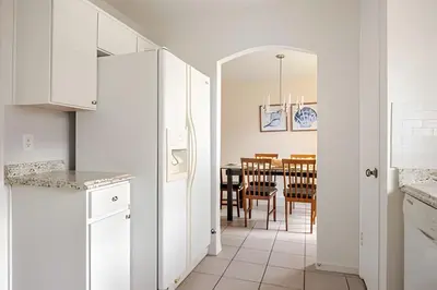 a kitchen and dining room with white cabinets and a table at Excelente Refúgio em Indian Wells c/ Piscina Priv! in Kissimmee