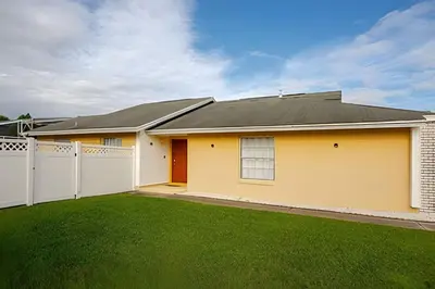 a yellow house with a fence and green grass at Excelente Refúgio em Indian Wells c/ Piscina Priv! in Kissimmee