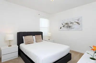 a white bedroom with a white bed and two lamps at Luxuosa Villa 9 Suítes c/ Piscina Sonoma Resort in Kissimmee