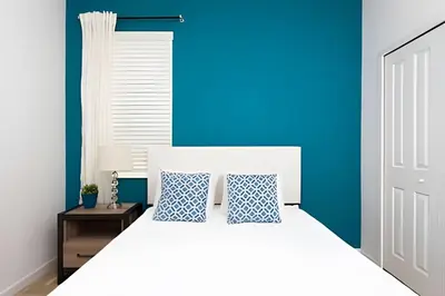 a bedroom with a white bed with a blue wall at Luxuosa Villa 9 Suítes c/ Piscina Sonoma Resort in Kissimmee