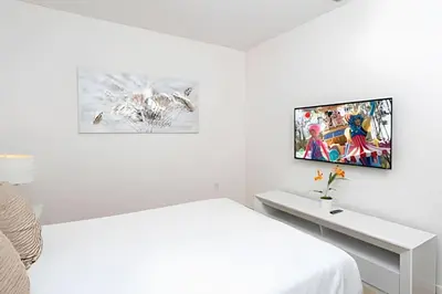 a white room with a bed and a tv on the wall at Luxuosa Villa 9 Suítes c/ Piscina Sonoma Resort in Kissimmee