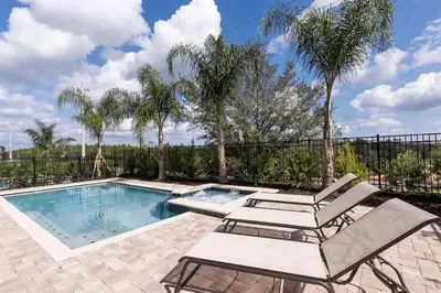 a swimming pool with two lounge chairs and palm trees at Luxury 9-Bedroom Villa with Pool Near Disney in Orlando