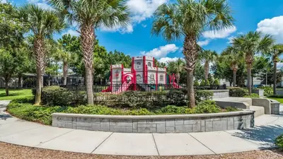 a red building with palm trees in front of a park at Private 6 Bed 4 Bath Villa- Cozy family vacation home sleeps up to 12 guests in Orlando