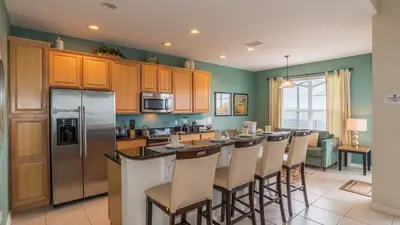 a kitchen with a bar with chairs and a refrigerator at Urban 4 Bed 4 Bath Villa- Perfect stay while exploring Orlando,Florida in Orlando