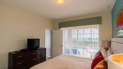 a bedroom with a bed and a television and a balcony at Urban 4 Bed 4 Bath Villa- Perfect stay while exploring Orlando,Florida in Orlando