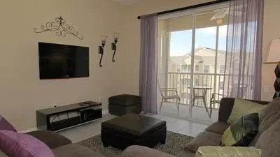 a living room with a couch and a tv and a balcony at GRH9192 - Windsor Hills Resort - 3 Bed 2 Baths Condo in Orlando