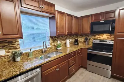 a kitchen with wooden cabinets and a sink and a window at Bungalow DT by Lake Eola KIA center Sleeps 12 in Orlando