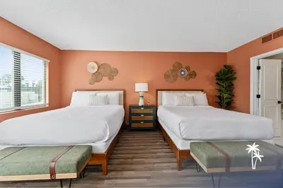 two beds in a room with orange walls at Boho Chic Garden Condo 7 Min to Universal Parks in Orlando