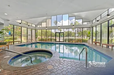 a large swimming pool in a building with windows at Boho Chic Garden Condo 7 Min to Universal Parks in Orlando