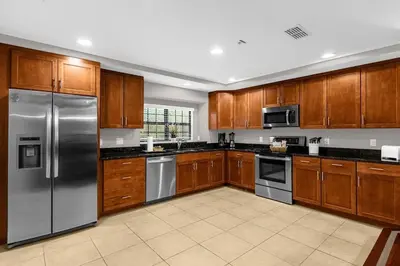 a kitchen with wooden cabinets and stainless steel appliances at Florida Summer - Townhome 5 min from Disney in Orlando