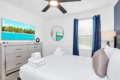 a bedroom with a white bed and a flat screen tv at Stunning 7BR Resort Pool Home 13 Min Disney in Kissimmee